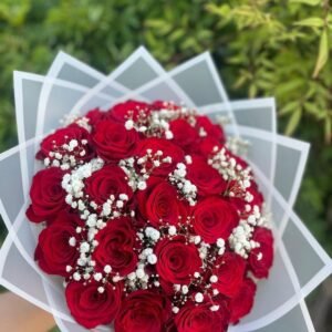 A stunning bouquet of deep red roses adorned with delicate baby's breath, wrapped in elegant white paper, perfect for expressing love and admiration.