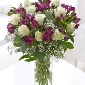 A stunning floral arrangement featuring elegant white roses, deep purple Alstroemeria, and delicate baby's breath, beautifully displayed in a clear glass vase, creating a timeless and sophisticated look.