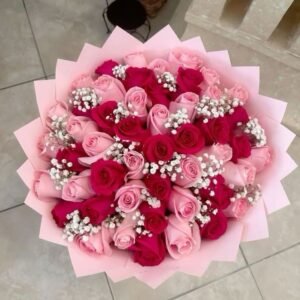 Bouquet of pink and red roses with baby's breath, wrapped in pink paper.