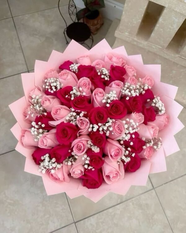 Bouquet of pink and red roses with baby's breath, wrapped in pink paper.