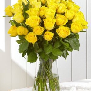 Vibrant bouquet of yellow roses arranged in a clear glass vase with lush green leaves, perfect for cheerful gifts and celebrations.