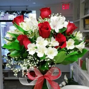 Elegant bouquet of red roses, white alstroemeria, and baby's breath with lush greenery, tied with a red ribbon.