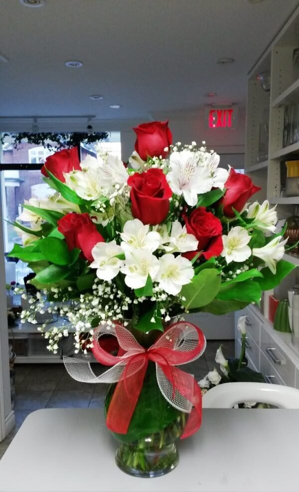 Elegant bouquet of red roses, white alstroemeria, and baby's breath with lush greenery, tied with a red ribbon.