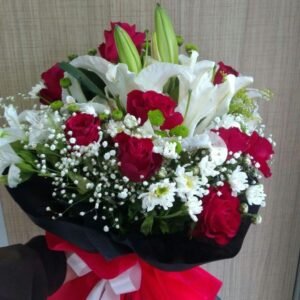 Elegant bouquet of red roses, white lilies, daisies, and baby's breath, wrapped in black and red with a decorative ribbon